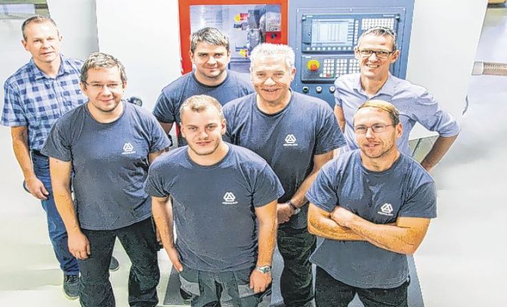Das CNC-Produktionsteam vor der neuen CNC-Drehmaschine (Foto: HENNLICH)