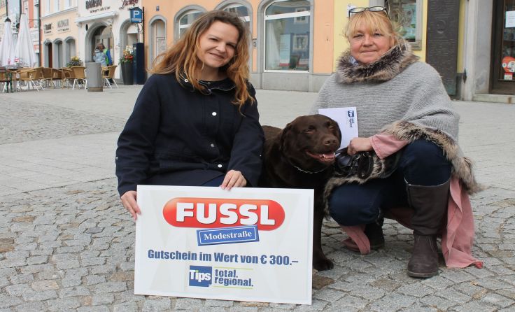 Redakteurin Elena Auinger (l.) übergibt den Gewinn an Beate Brandt und Hund Leo.