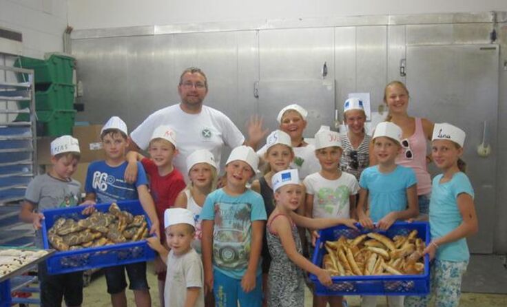 Die Kinder in der Backstube mit ihren selbst hergestellten Backwaren.