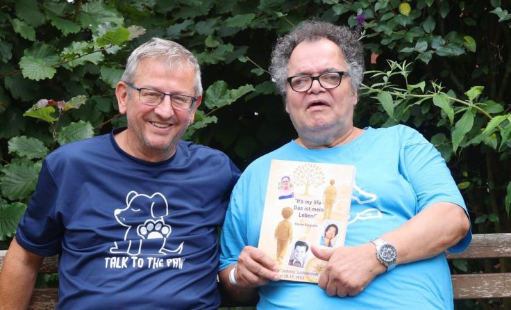 Peter Schneider (l.) mit Johnny, der stolz seine Lebensgeschichte in Händen hält. (Foto: Caritas)