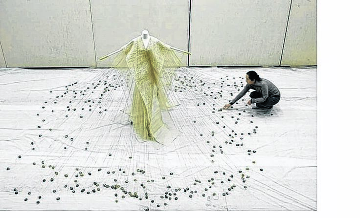 Li Qing baut ihre Arbeit „Rain“ mit Kieselsteinen an Schnüren auf.