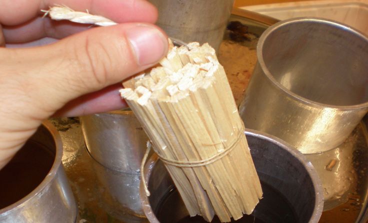 Die Anzündhilfen aus Holzstäbchen werden in helles Wachs getaucht. Foto: Lebenshilfe OÖ