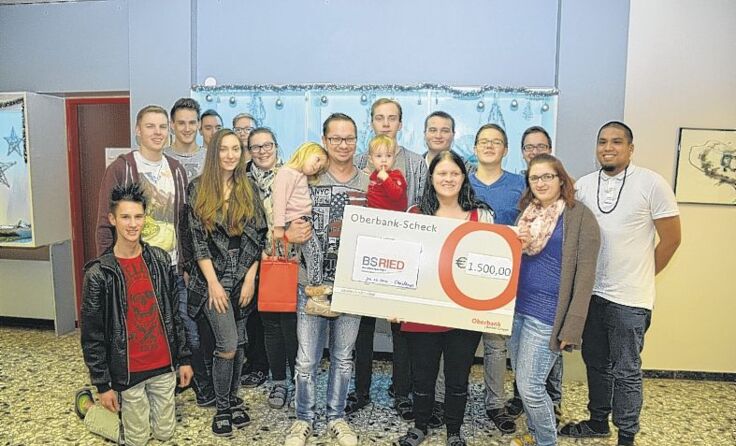 Die Schüler übergeben den Scheck an die Familie.