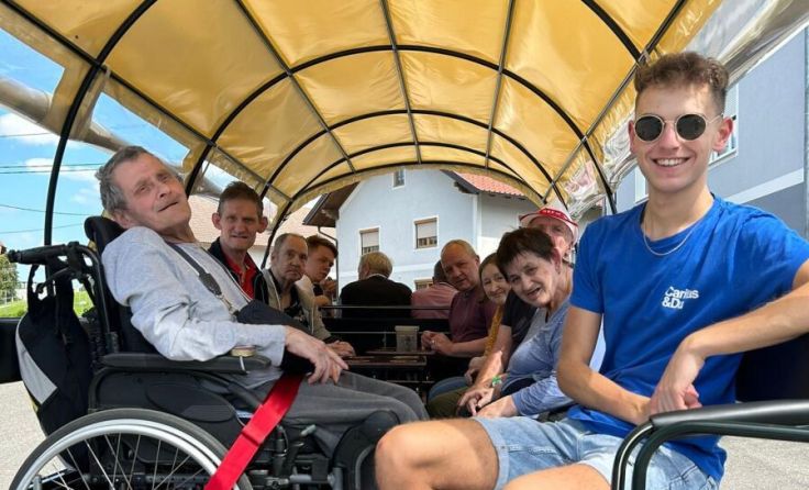 Der Zivildiener Sebastian Probst mit den Bewohnern auf dem Traktor Rudi (Foto: Caritas)