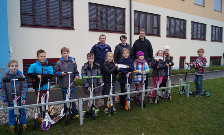 Schüler freuen sich mit deren Eltern über neuen Scooter-Ständer