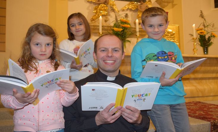 Pfarrer Christoph Weiss mit Kindern und dem Youcat for Kids; Foto: Wolfgang Zarl