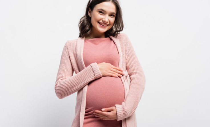 joyful pregnant woman touching belly on white (Foto: adobeStock/LIGHTFIELD STUDIOS)